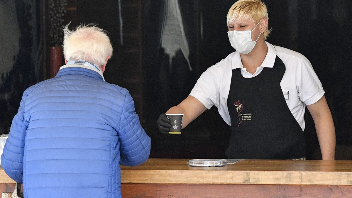 A waiter serves a coffee to go at an ice cream parlor in Gelsenkirchen, Germany, as many smaller stores are allowed to open on April 20, 2020.