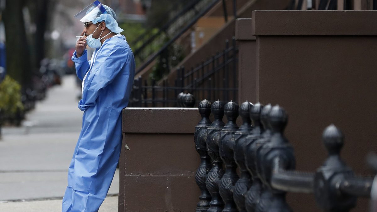 An emergency room nurse leans against a stoop as he takes a break from his work at the Brooklyn Hospital Center on Sunday.